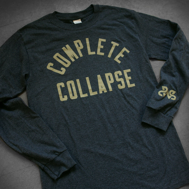 close up, angled image of a dark heather grey long sleeve tee laid flat on a concrete floor. tee has center chest print in tan that says complete collapse and small print on the bottom right sleeve of the letters S W S