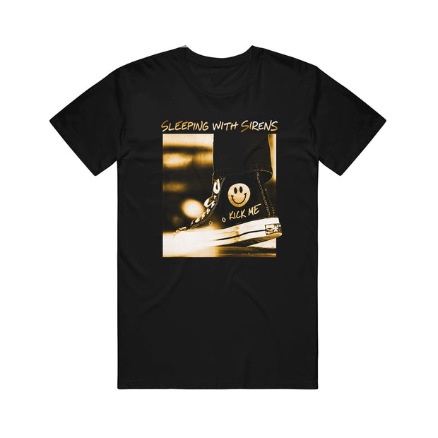 This black t-shirt by Sleeping With Sirens features a sepia photo of a sneaker with a smiley face and "KICK ME," plus the band's name in bold, white handwritten-style text above.