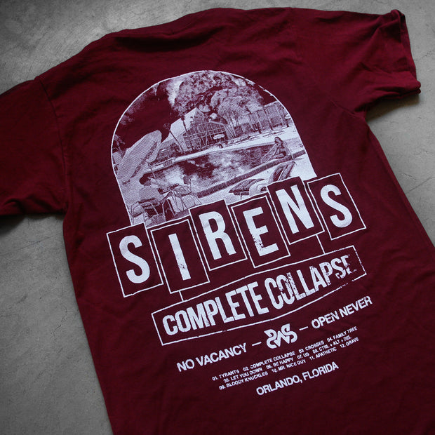 close up. angled image of the back of a maroon tee shirt laid flat on a concrete floor. back of tee has a full back print in white. in the center says sirens, above is an image of a motel pool, and below says compete collapse no vacancy, open never, and the track list to their album